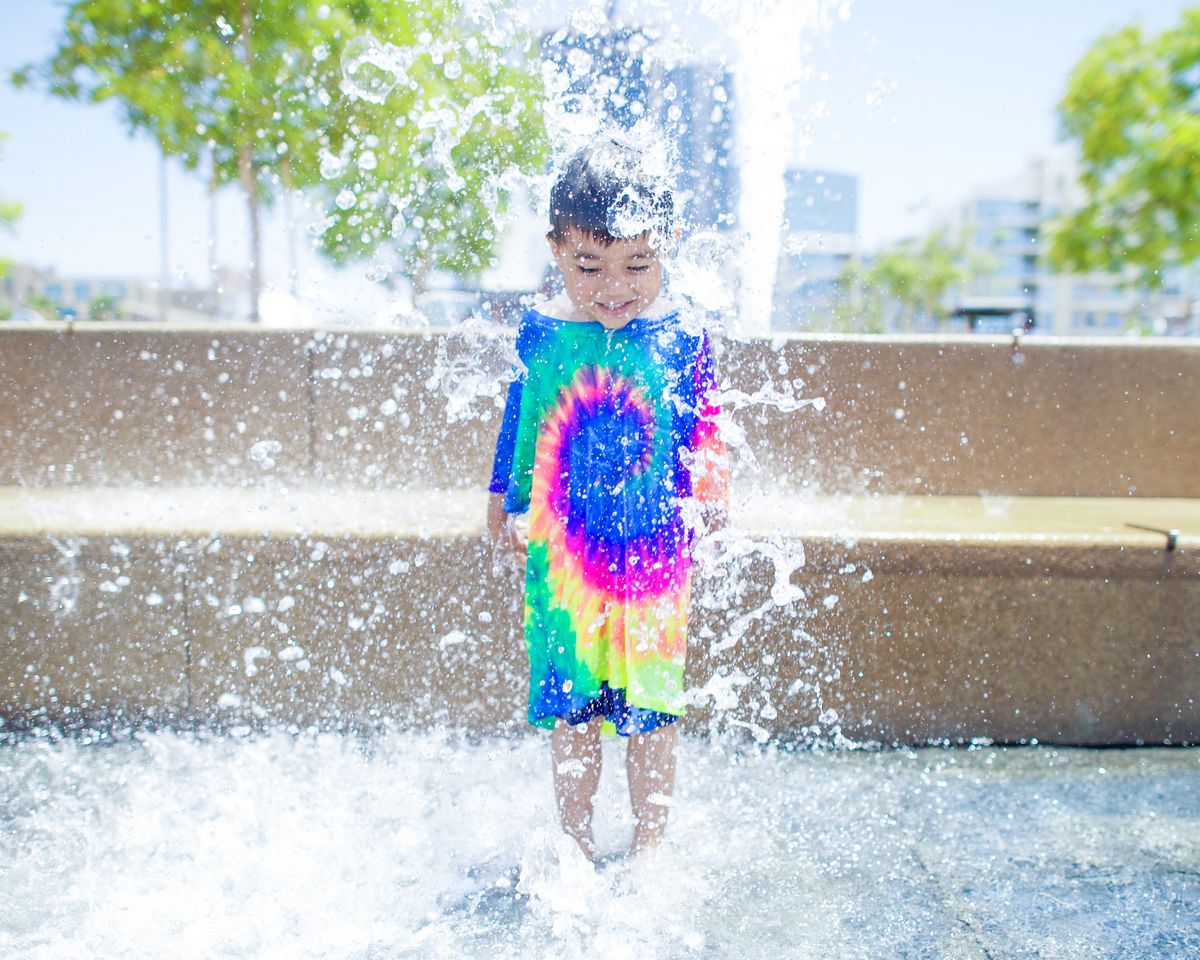 A child jumping on a splash pad in the city.