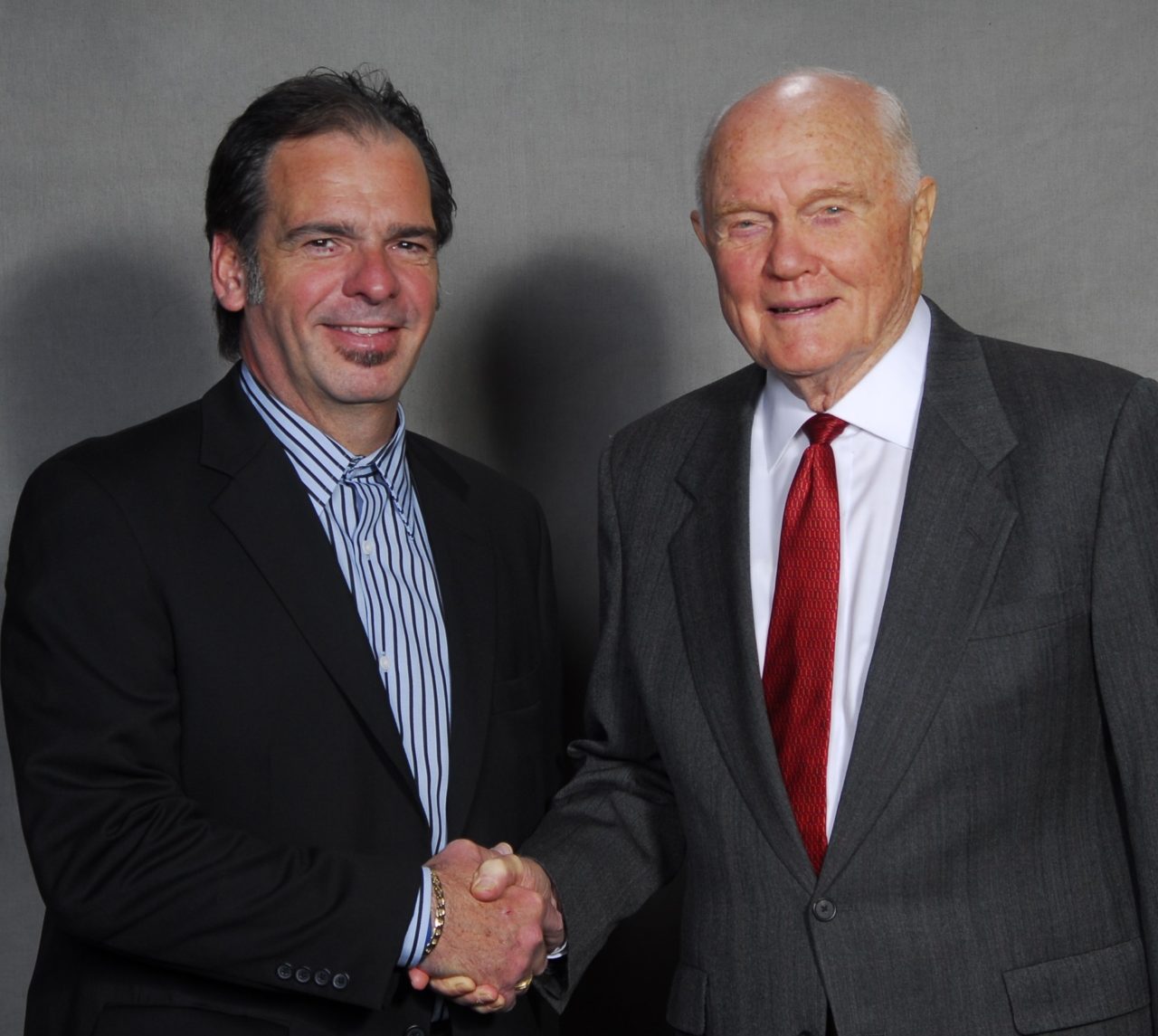 Two men facing the camera shaking hands.